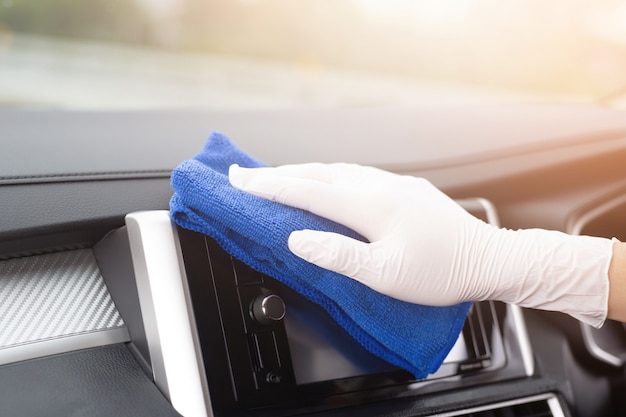 Un travailleur main porter des gants de nettoyage du volant de console de voiture avec un chiffon en microfibre