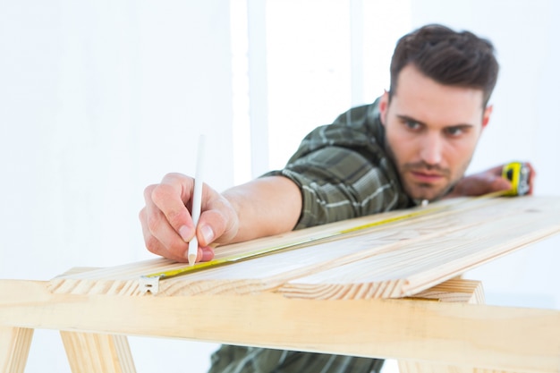 Travailleur de marquage sur une planche en bois