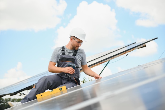 Travailleur masculin avec des batteries solaires Homme dans un casque de protection Installation d'un système de panneaux solaires autonome