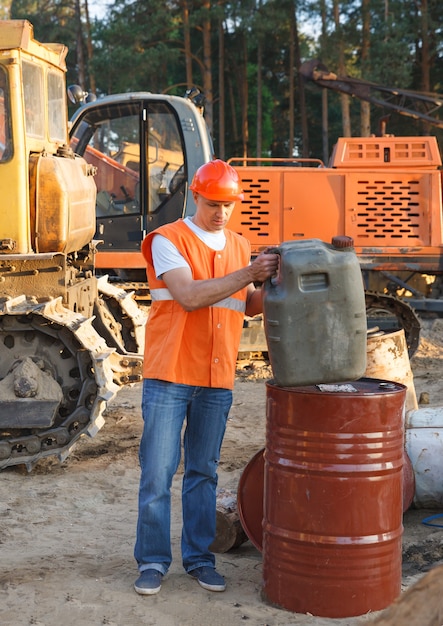 Travailleur masculin en casque tenant une cartouche de carburant pour les machines de construction