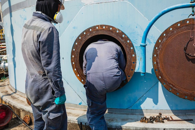 Travailleur masculin dans la zone d'interface d'huile chimique de carbone du réservoir sécurité de l'espace confiné.