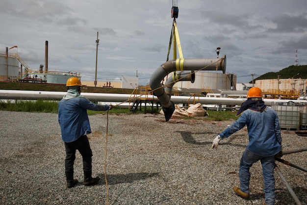 Travailleur masculin le frondeur au travail de grue. Déchargement par la grue de l'équipement de production d'huile et de vannes du pipeline.