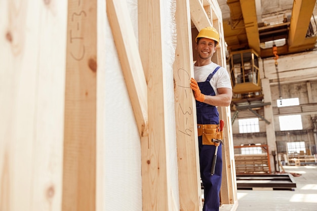 Travailleur masculin gai se tenant dans la carlingue en bois de construction