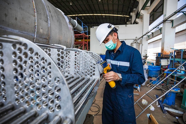 Travailleur masculin inspectant la surface sur l'entrepôt de construction industrielle de faisceau de tubes d'échangeur de chaleur positif