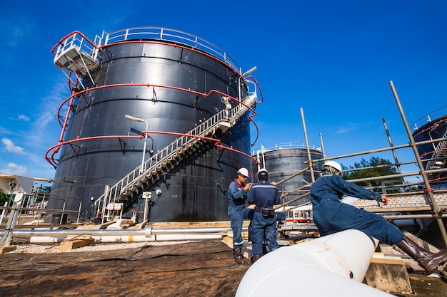 Un travailleur masculin inspecte le pipeline visuel et le pétrole brut du réservoir de stockage