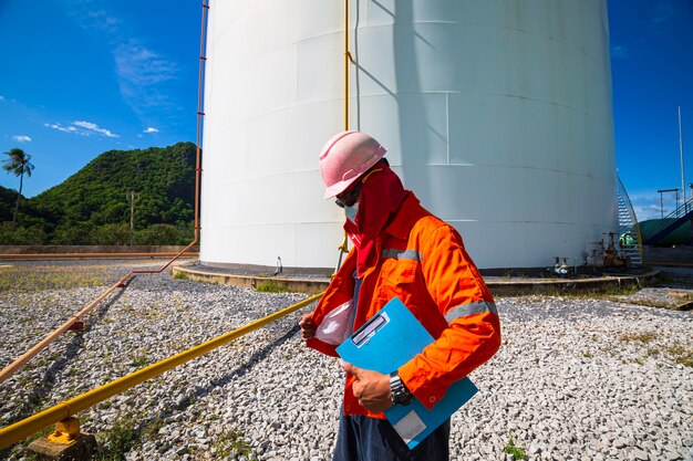 Photo travailleur masculin inspection visuelle du réservoir de pétrole et de gaz.