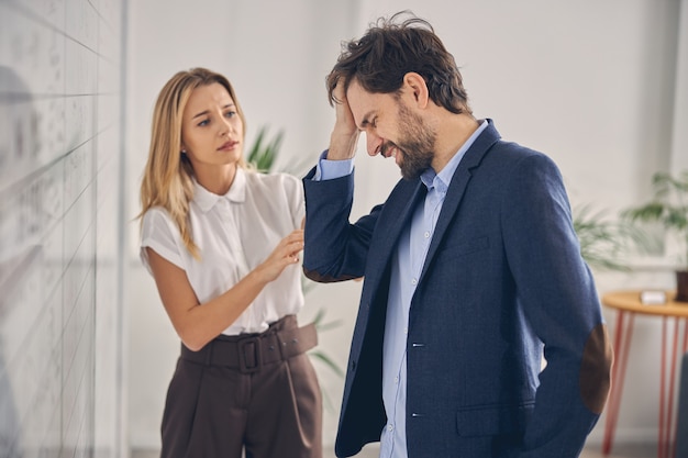 Travailleur masculin souffrant de migraine tandis qu'une collègue le regarde avec une expression inquiète