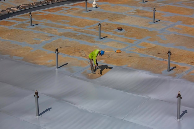 Un travailleur masculin tenant un pistolet de pulvérisation industriel utilisé pour la surface du réservoir de la plaque de toit sur la peinture industrielle en acier