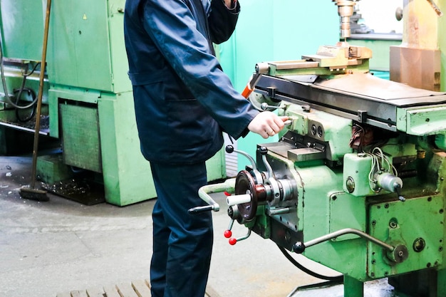 Un travailleur masculin travaille sur un plus grand équipement de tour de serrurier en fer métallique pour réparer le travail du métal