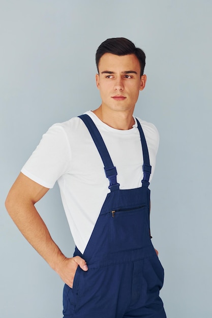 Travailleur masculin en uniforme bleu debout à l'intérieur du studio sur fond blanc