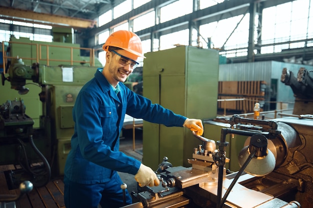 Un travailleur masculin en uniforme et un casque vérifient le tour sur l'usine