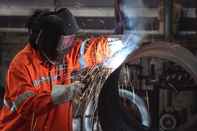 Un Travailleur Avec Un Masque De Protection Soudant Des Tuyaux Métalliques Dans Une Usine