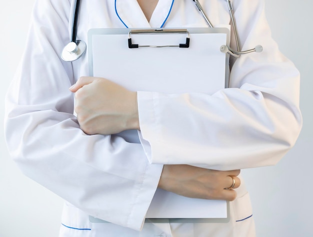 Un travailleur médical en blouse blanche avec un stéthoscope tient un presse-papiers dans ses mains