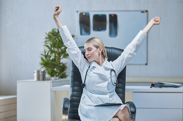 Le travailleur médical du bureau a terminé son travail et s'étire les mains en l'air