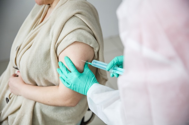 Un travailleur médical en gants verts donne à une femme un coup de poing dans l'épaule 19