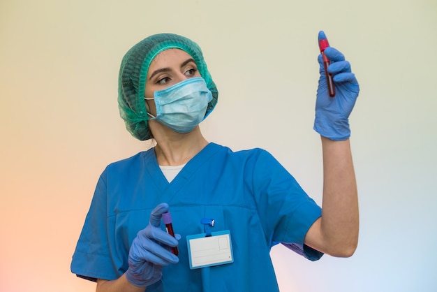 Travailleur médical avec des tubes à essai avec pose de sang en laboratoire. Belle femme en uniforme de protection