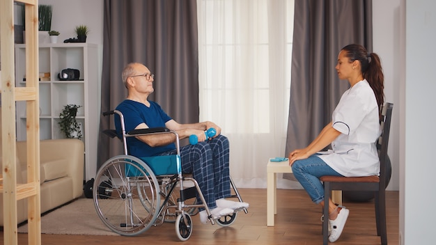 Travailleur médical avec un vieux patient en fauteuil roulant faisant de la physiothérapie. Personne âgée handicapée handicapée avec travailleur social dans la thérapie de soutien au rétablissement du système de santé de la physiothérapie hom de retraite de soins infirmiers