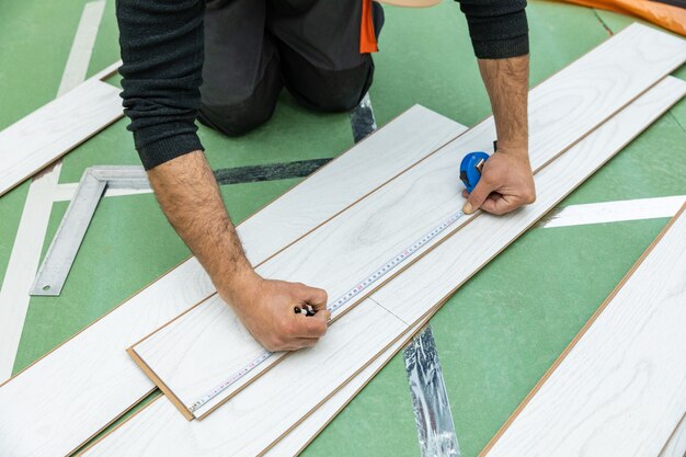 Photo travailleur mesure la longueur du stratifié en bois blanc