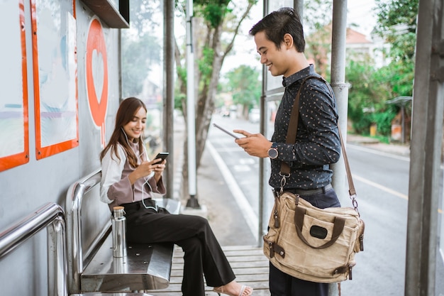 Travailleur occupé à utiliser son gadget en attendant les transports en commun