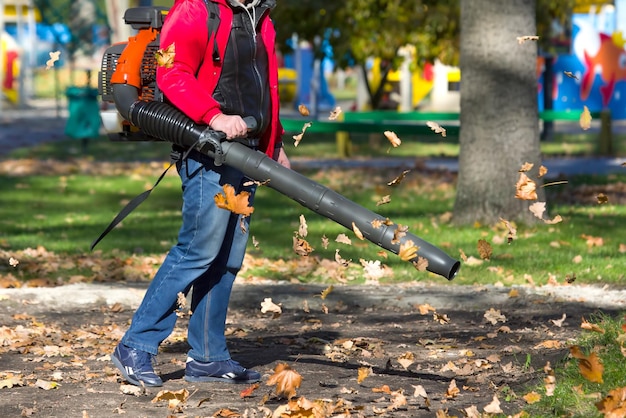 Travailleur opérant un souffleur de feuilles à usage intensif dans le parc de la ville Retrait des feuilles mortes en automne Service de nettoyage du parc