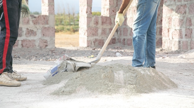 Le travailleur prépare le béton avec une pelle sur le chantier de construction.