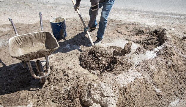 Le travailleur prépare le béton avec une pelle sur le chantier