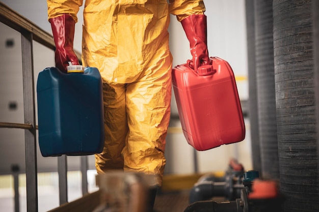 Travailleur de produits chimiques méconnaissable transportant des bidons en plastique à l'intérieur de l'usine