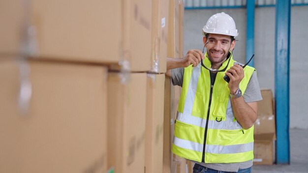 Un travailleur professionnel du fret parle sur une radio portable pour contacter un autre travailleur Concept de communication d'usine et d'entrepôt