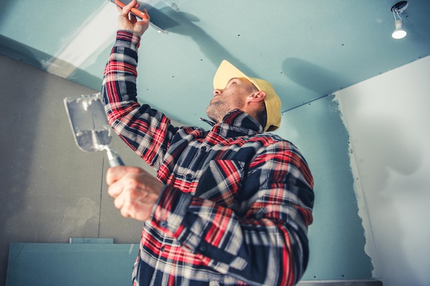 Travailleur professionnel de finition d'intérieur réparant le plafond de la pièce