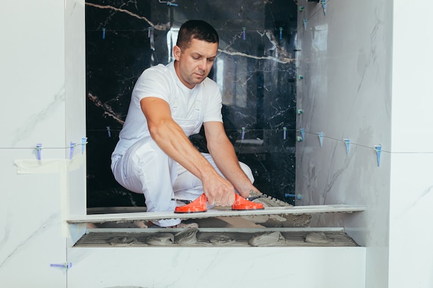 Un travailleur professionnel monte des carreaux de céramique dans la salle de bain