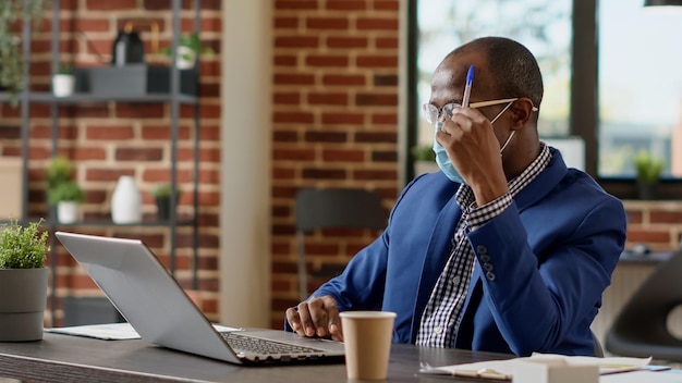 Un travailleur réfléchi réfléchit à des idées pour créer un plan de projet avec des statistiques en ligne. Employé incertain se sentant pensif et pensant à une nouvelle stratégie commerciale pendant la pandémie.