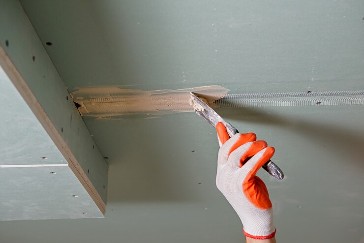 Travailleur remplissant les plaques de plâtre joint le mastic de gypse