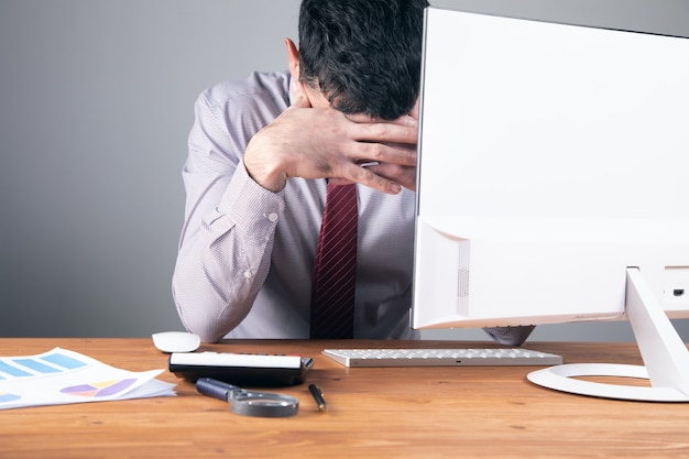 Le travailleur s'est couvert le visage alors qu'il était assis à son bureau.