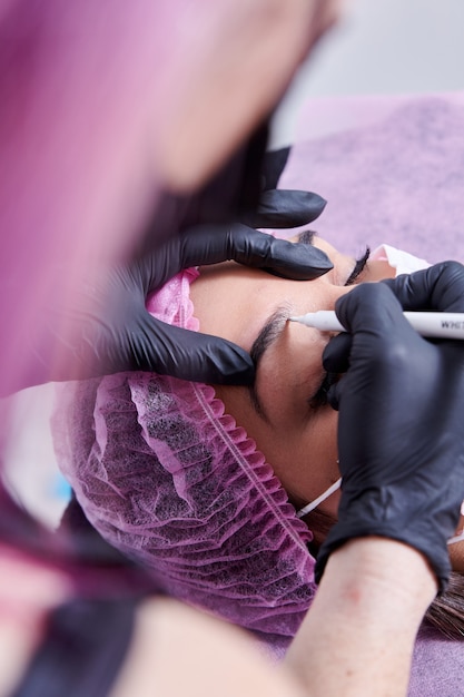 Photo travailleur de salon de beauté microblading les sourcils d'un client