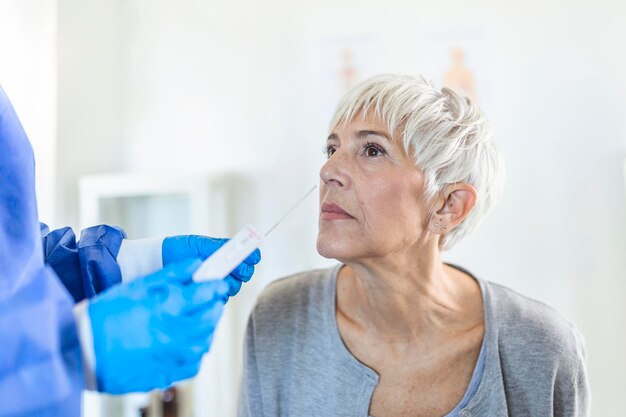 Photo un travailleur sanitaire portant un équipement de protection effectue un frottement du coronavirus sur une femme mature un frottement nasal pour le covid-19