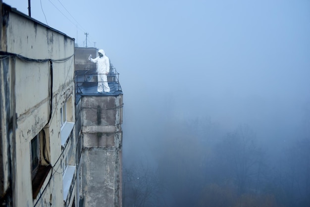 Travailleur scientifique portant une combinaison de protection et un masque à gaz faisant des tests écologiques sur le toit