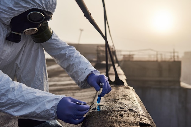 Travailleur scientifique portant une combinaison de protection et un masque à gaz faisant des tests écologiques sur le toit