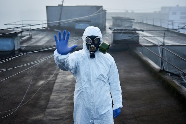 Travailleur scientifique portant une combinaison de protection et un masque à gaz faisant des tests écologiques sur le toit