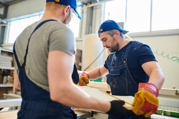 Travailleur sérieux vérifiant la taille d'une pièce de meuble