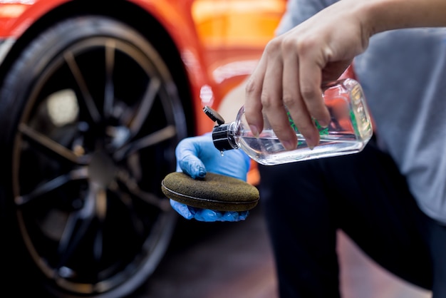 Travailleur de service automobile polissage des roues de voiture avec un chiffon en microfibre.