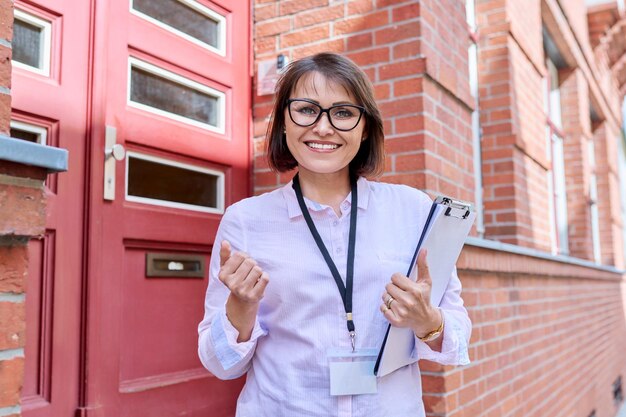 Travailleur social regardant la caméra sur le fond de l'entrée principale d'un immeuble d'appartements service social soins aider les gens concept