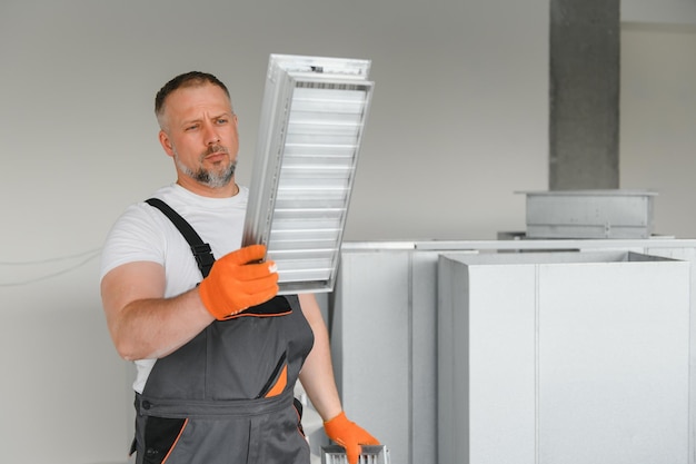 Travailleur tenant un filtre à air pour l'installation dans le système de ventilation du bureau Pureté du concept d'air