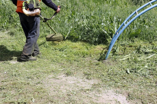 Le travailleur tond l'herbe avec une tondeuse