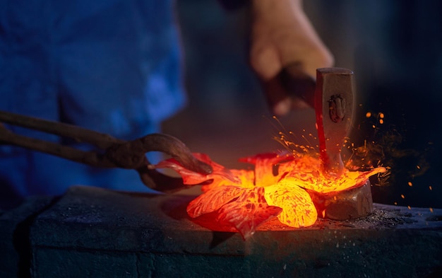 Travailleur en uniforme bleu faisant du métal avec le feu en forge