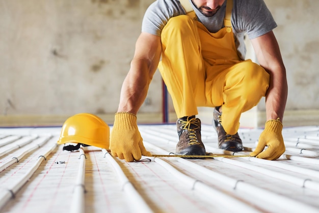 Travailleur en uniforme de couleur jaune installant un système de chauffage par le sol