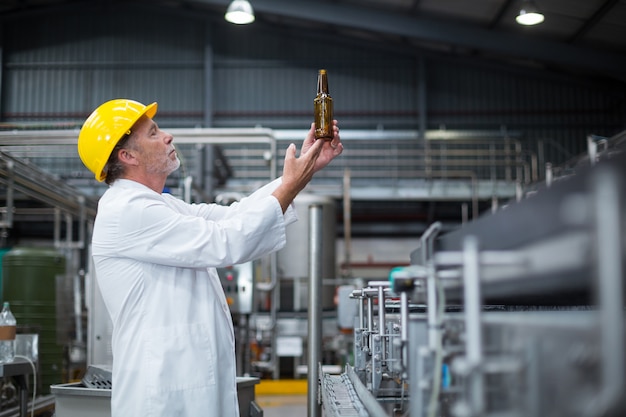 Travailleur d'usine examinant une bouteille en usine