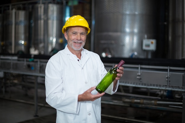 Travailleur d'usine examinant une bouteille en usine