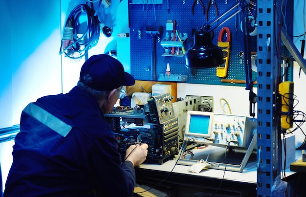 Photo un travailleur utilise un testeur pour diagnostiquer et réparer des équipements complexes dans une usine dans un atelier de réparation.