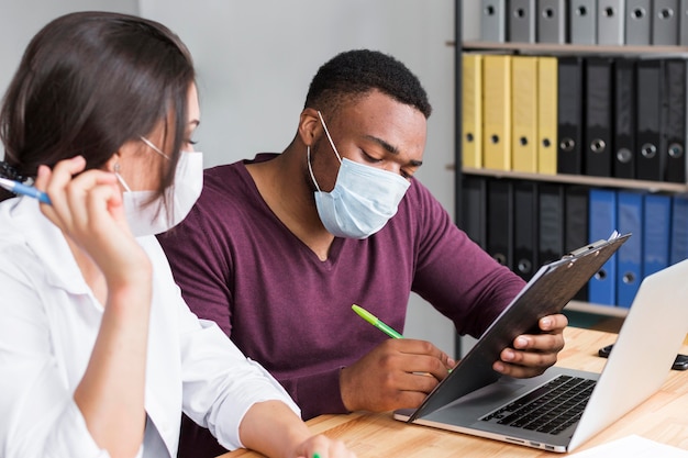 Photo travailleurs au bureau pendant la pandémie portant des masques médicaux