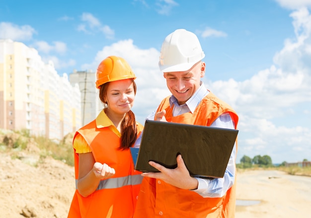 Travailleurs De La Construction, Femmes Et Hommes, Regardant Un Ordinateur Portable De Maisons En Construction